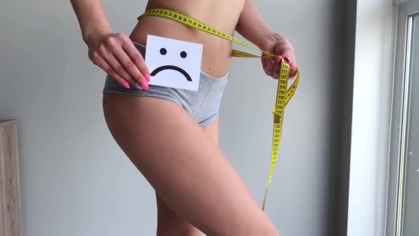 Υγεία της γυναίκας. Γυναικείου σώματος κρατώντας θλιβερό χαμόγελο κάρτα κοντά στο στομάχι — Αρχείο Βίντεο