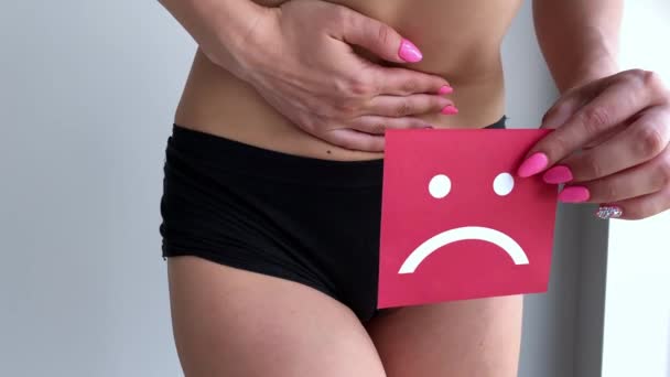 Salud de la mujer. Cuerpo femenino sosteniendo triste tarjeta sonriente cerca del estómago — Vídeo de stock