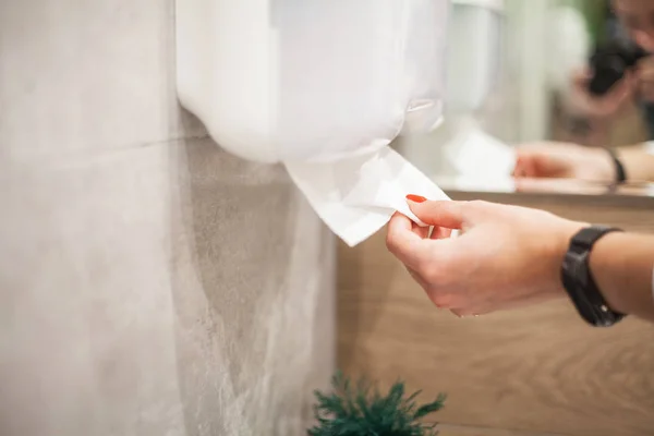 Kadının eli banyoda kağıt havlu alır..