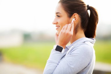 Neşeli Fitness kadın 30'lu Bluetooth Earpod dokunmadan ve Green Park'ta dinlenme sırasında cep telefonu, tutan spor giyim fotoğrafı