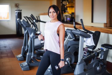 Genç ve çekici bir kadın spor salonunda egzersiz yapıyor..