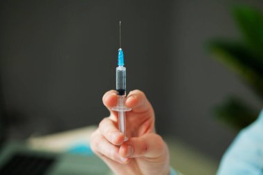 Klinikte elinde şırınga tutan doktor.