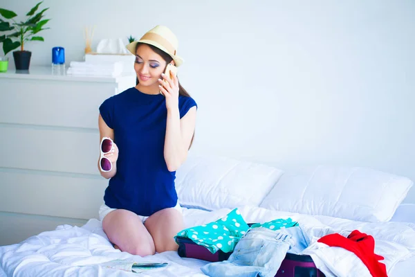 Mulher bonita recolhe roupas em mala de viagem em uma viagem — Fotografia de Stock