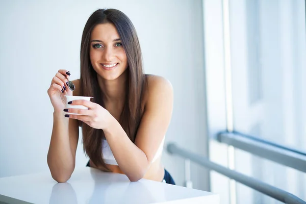 Glad ung kvinna äta yoghurt i köket — Stockfoto