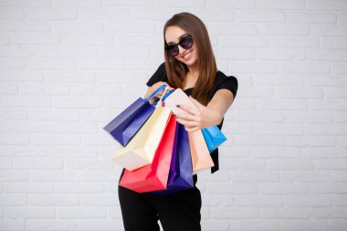 Siyah Cuma tatilinde açık arkaplanda renkli çantalar taşıyan bir kadın.