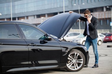 Yolun ortasında kırık arabalı bir adam var.