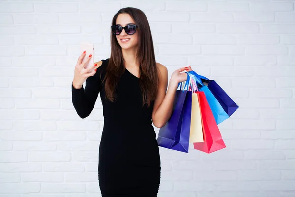 Woman holding colored bags on light background in black friday holiday — Stock Photo, Image