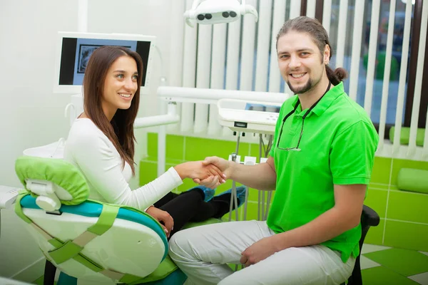 Dentista em consultório odontológico conversando com paciente do sexo feminino e se preparando para o tratamento — Fotografia de Stock