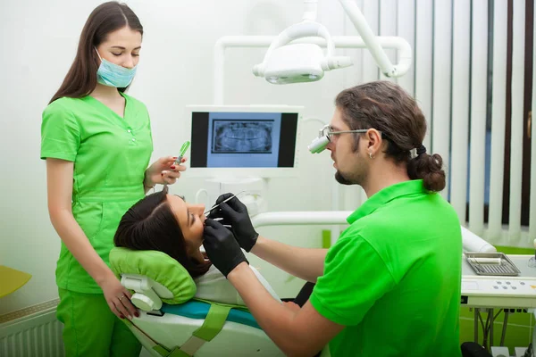 O dentista está a tratar dos dentes ao cliente no consultório dentário. — Fotografia de Stock