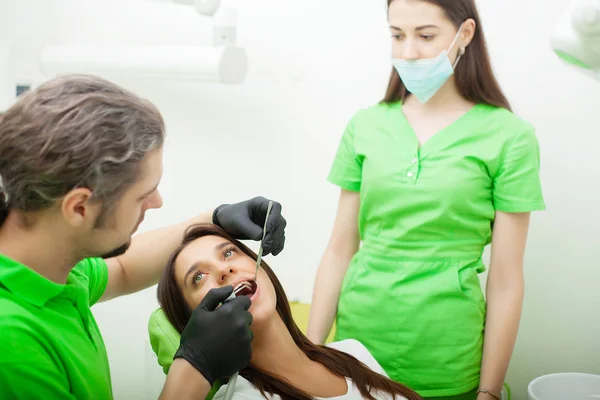 Dentista estão tratando dentes para cliente em consultório odontológico — Fotografia de Stock