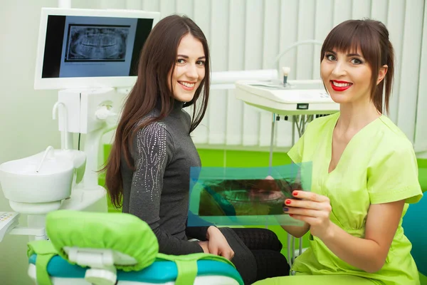 Dentista en el consultorio dental hablando con la paciente femenina y preparándose para el tratamiento —  Fotos de Stock