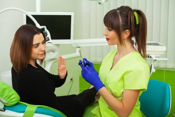 Dentista nello studio dentistico che parla con una paziente e si prepara per il trattamento — Foto Stock
