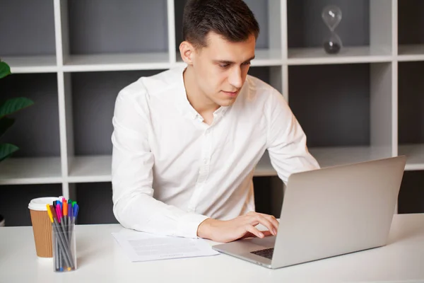 Podnikatel sedící za kancelářským stolem a pracující na notebooku — Stock fotografie