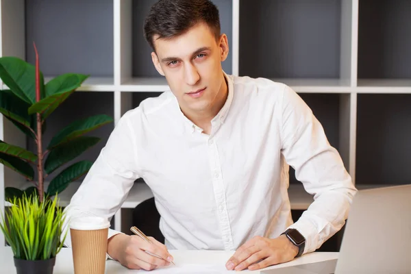 Podnikatel sedící za kancelářským stolem a pracující na notebooku — Stock fotografie