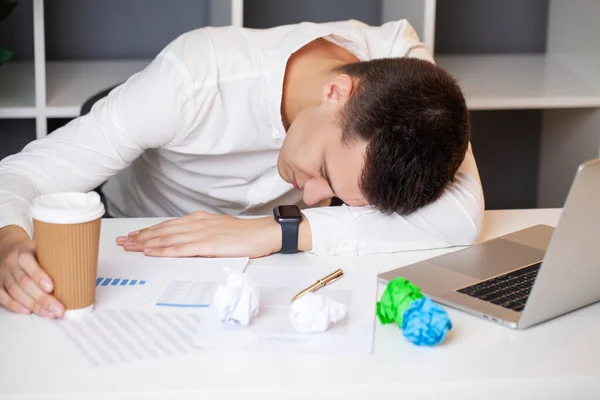 Уставший бизнесмен спит на ноутбуке в офисе — стоковое фото