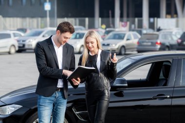 Mutlu genç çift aile için yeni bir araba seçer ve alır.