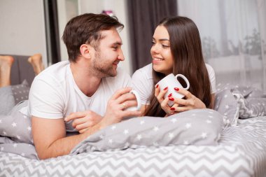 Mutlu, şehvetli, genç çift yatakta birlikte yatıyor.