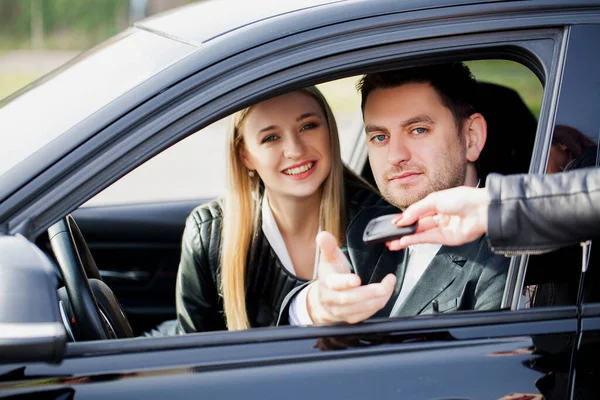 Feliz joven pareja elige y compra un coche nuevo para la familia — Foto de Stock