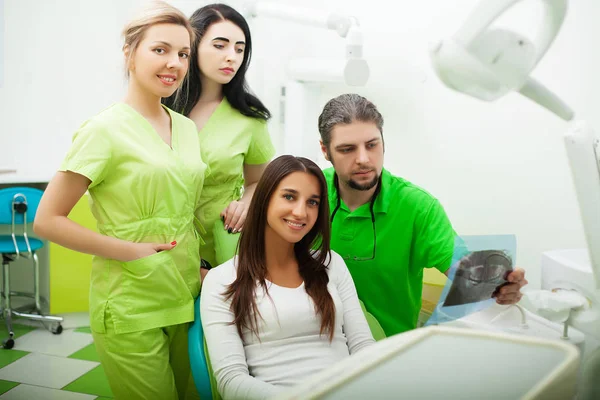Jovem dentista tratando uma paciente do sexo feminino no estúdio odontológico — Fotografia de Stock