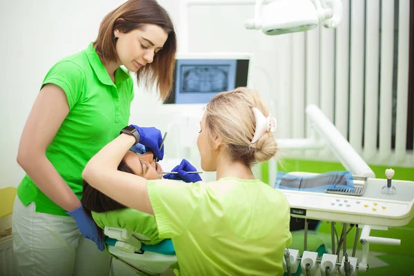 Joven dentista tratando a una paciente femenina en el estudio dental —  Fotos de Stock