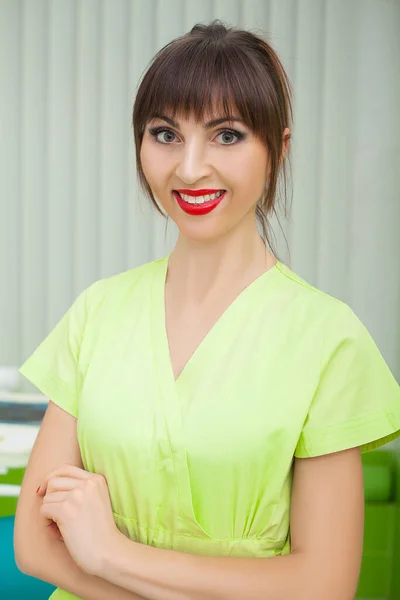 Jovem dentista feminina de casaco verde no local de trabalho . — Fotografia de Stock