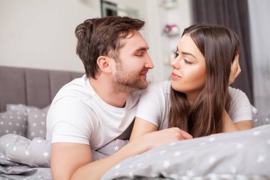 Mutlu, şehvetli, genç çift yatakta birlikte yatıyor.