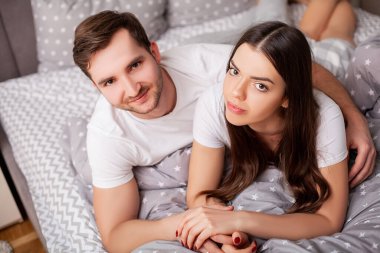 Mutlu, şehvetli, genç çift yatakta birlikte yatıyor.