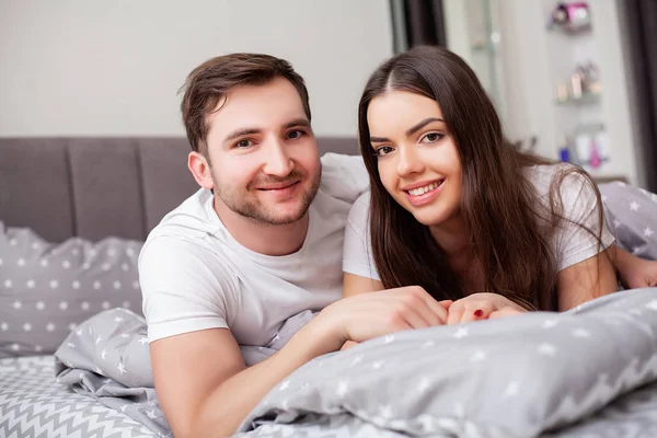 Feliz sensual joven pareja acostada en la cama juntos —  Fotos de Stock