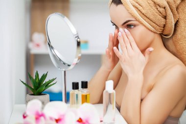 Kadın sabah makyajını evde banyo aynasında yapmaya hazırlanıyor..