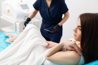 Bir kadın güzellik salonunda lazer tedavisi görüyor.