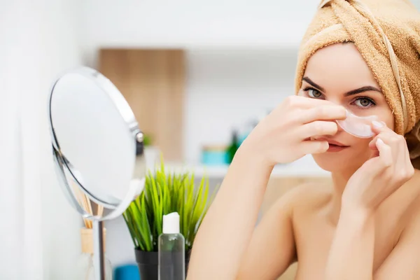 Mujer atractiva joven con parches bajo los ojos mirando al espejo — Foto de Stock