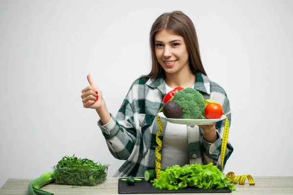 Mulher bonita jovem adere à dieta e mantém um prato de legumes — Fotografia de Stock