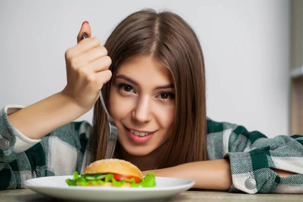 Young pretty woman adheres to diet but chooses unhealthy food