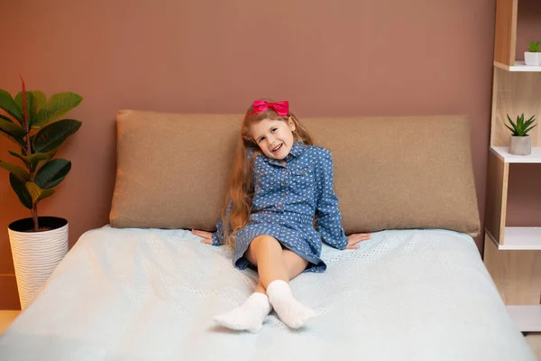 Menina sentada na cama no quarto — Fotografia de Stock