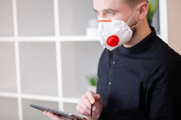 Man in protective mask working at tablet in office — Stock Photo, Image