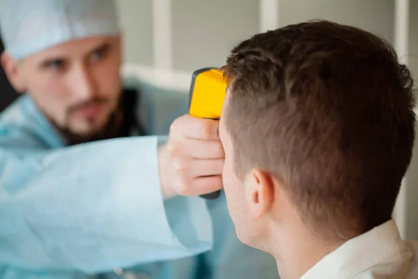 Médico mede a temperatura dos pacientes com um termômetro a laser — Fotografia de Stock