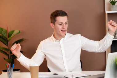 Dizüstü bilgisayarda çalışan mutlu genç adam işten memnun..