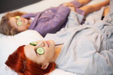 Anne ve kızı evde, yatakta spa tedavisi görüyor.