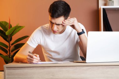 Ofisteki bilgisayarda çalışan ve belgeleri dolduran adam.