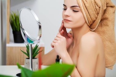 Kadın sabah makyajını evde banyo aynasında yapmaya hazırlanıyor.