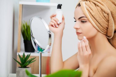Kadın sabah makyajını evde banyo aynasında yapmaya hazırlanıyor.