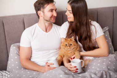 Mutlu, şehvetli, genç çift yatakta birlikte yatıyor..