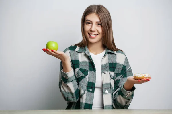 La mujer hace una elección entre alimentos saludables y dañinos —  Fotos de Stock