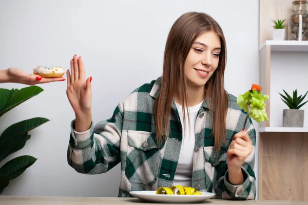 Kobieta dokonuje wyboru pomiędzy zdrową i szkodliwą żywnością — Zdjęcie stockowe
