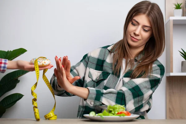 Mulher faz uma escolha entre alimentos saudáveis e prejudiciais — Fotografia de Stock