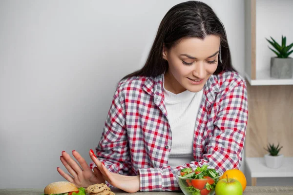 Kvinna gör ett val mellan hälsosam och skadlig mat — Stockfoto