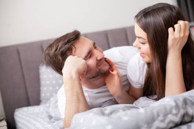 Mutlu, şehvetli, genç çift yatakta birlikte yatıyor..