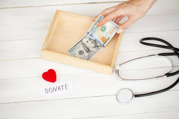 Charity-Spendenbox mit Dollars auf weißem Holzhintergrund — Stockfoto