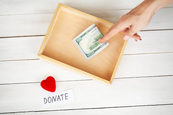 Коробка благодійного фонду з доларами на білому дерев'яному фоні — стокове фото