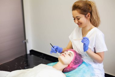 Kadın yüz bakımı için kozmetik maske takıyor.